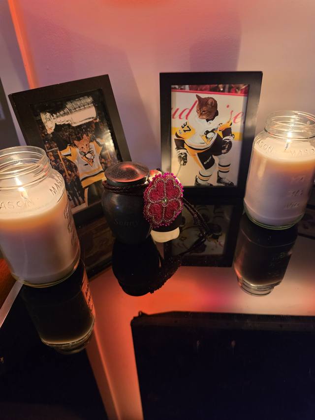 Sonny's altar: his urn with a beaded flower, his framed portraits, and candles
